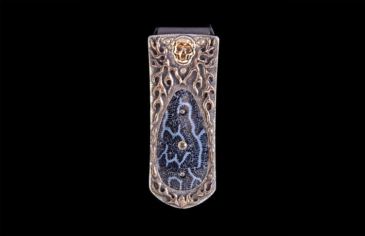 Silver money clip with a gold skull, flame design, and a black and white fossil coral inlay featuring clear stones.