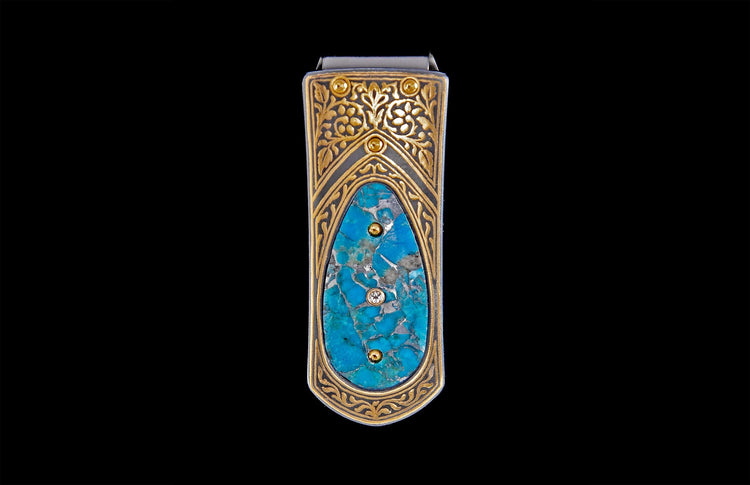 Ornate money clip featuring a central turquoise stone with a clear gemstone, framed by gold filigree and two gold studs.