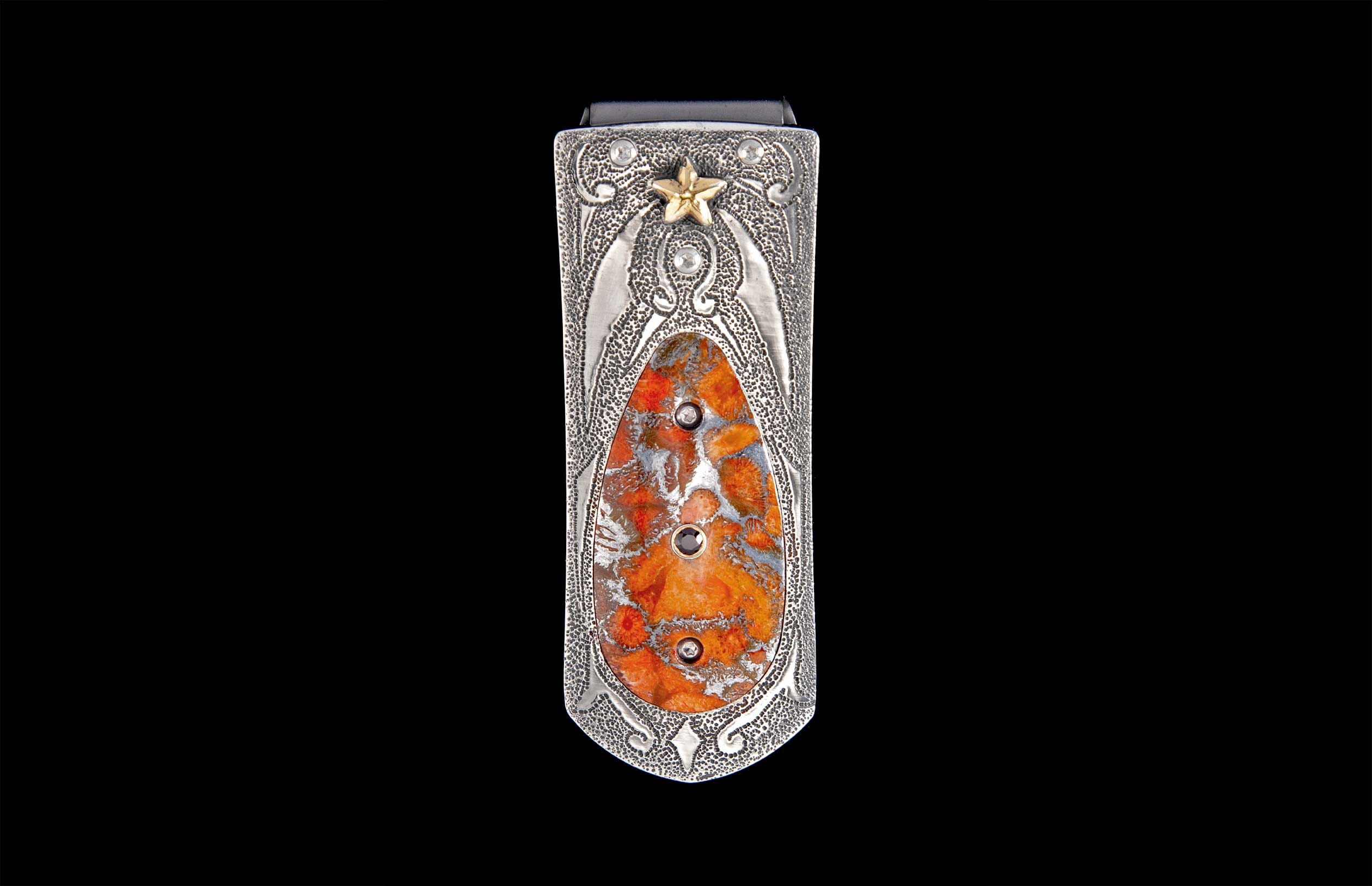 Silver-toned money clip with a textured surface, featuring an oval orange stone inlay, three dark cabochons, and a gold star accent.