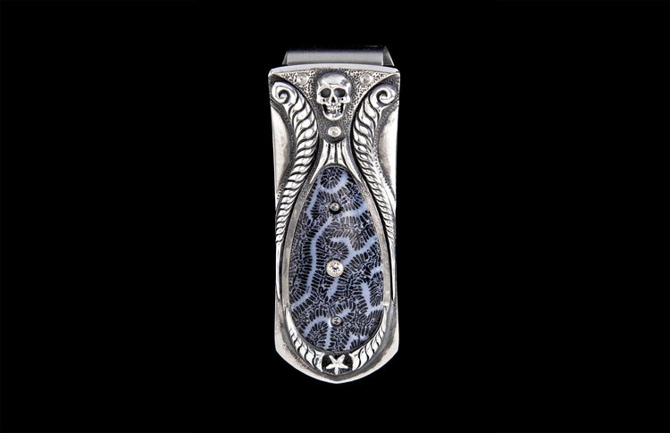 Ornate silver-toned money clip with a skull, leafy scrollwork, and a black-and-white fossilized coral inlay featuring clear gemstones and a star.