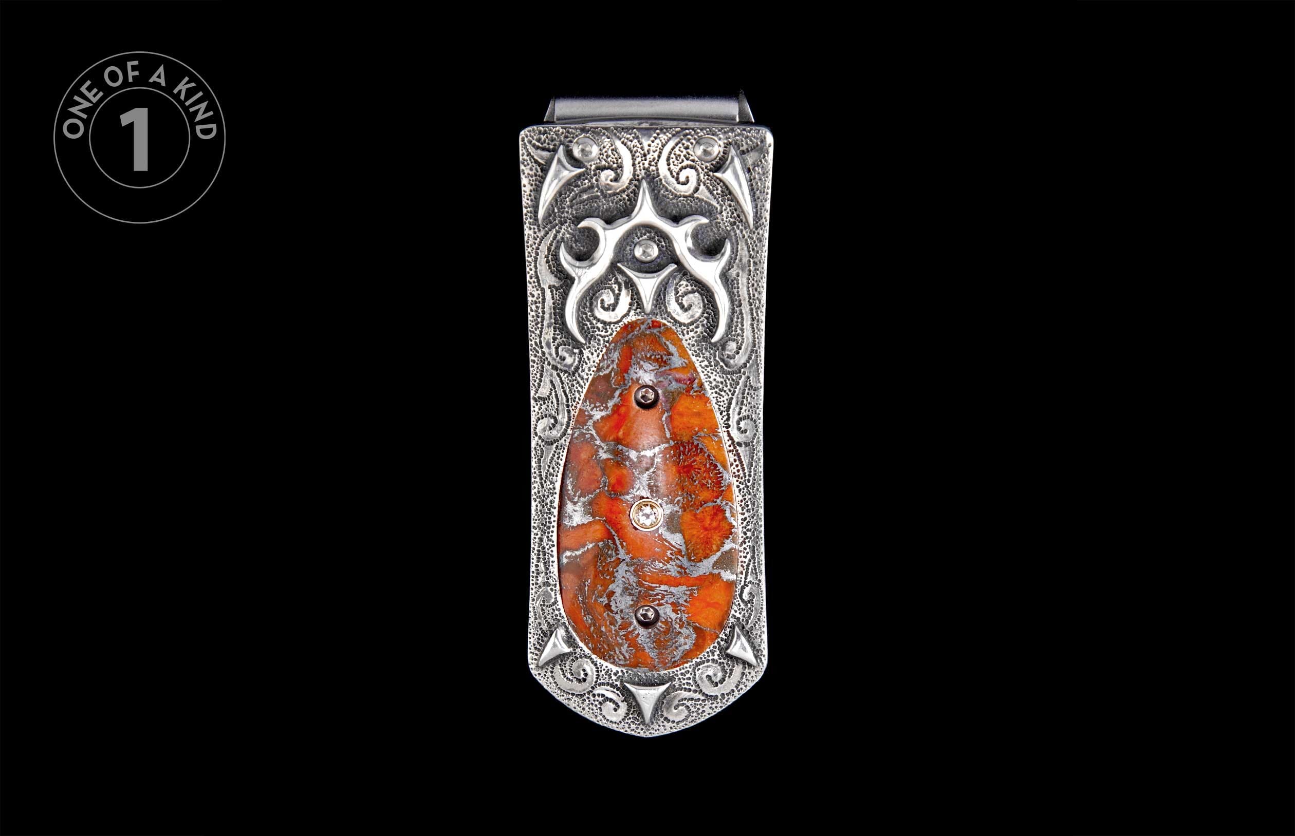 Ornate silver-toned metal money clip with intricate scrollwork, an oval orange-red patterned stone inlay, and three small round accents.