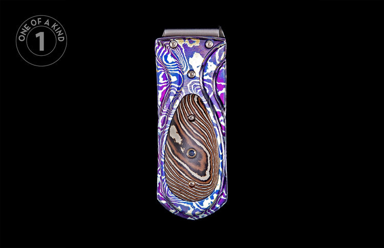 Vibrant patterned money clip with purple, blue, white, and gold swirls and a central brown and white striped inlay.