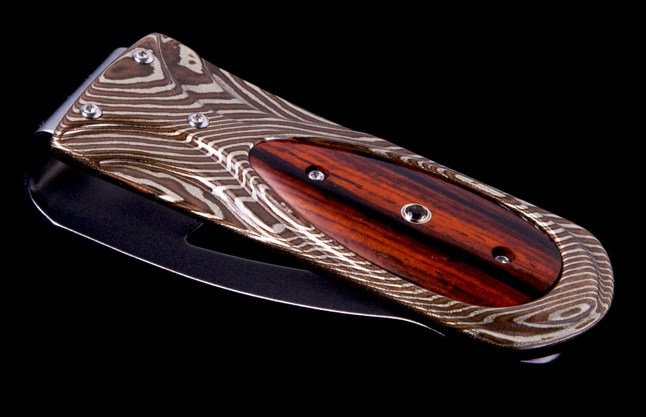 Folding money clip by M3 with brown and silver Damascus pattern, dark wood inlay, angled view.