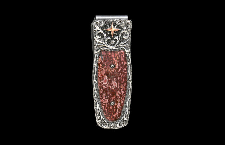 Silver money clip with an ornate textured frame, featuring a reddish-brown patterned stone inlay, a copper-toned star, and scroll details.