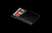 MCW MC BLK|Black leather card and cash wallet with two credit cards partially visible in the slots.