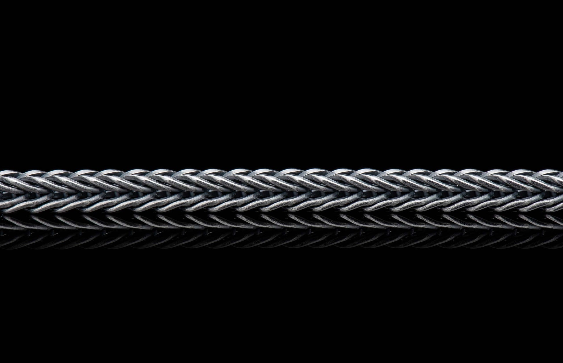 VESTA silver jewelry chain with a tightly woven Byzantine link pattern, horizontal, and subtle reflections.
