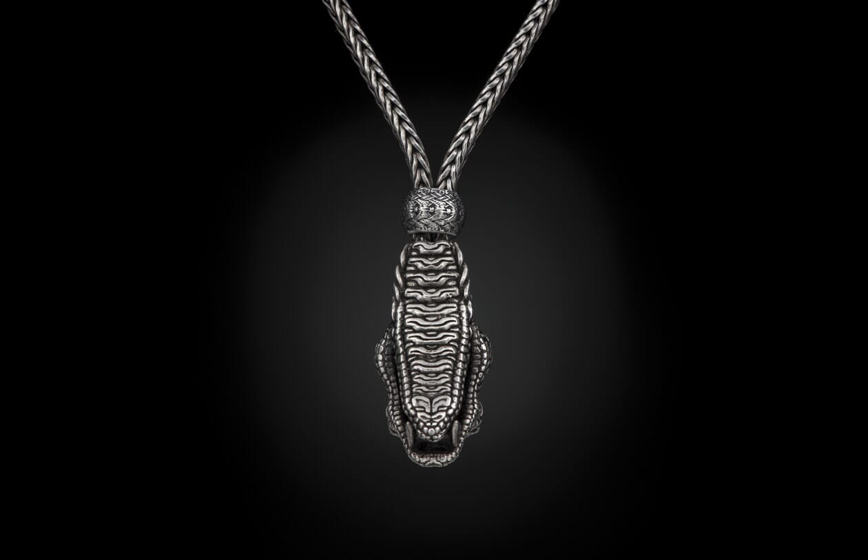 Silver-toned braided necklace featuring a detailed crocodile head pendant with an open mouth, connected by an ornate bead.