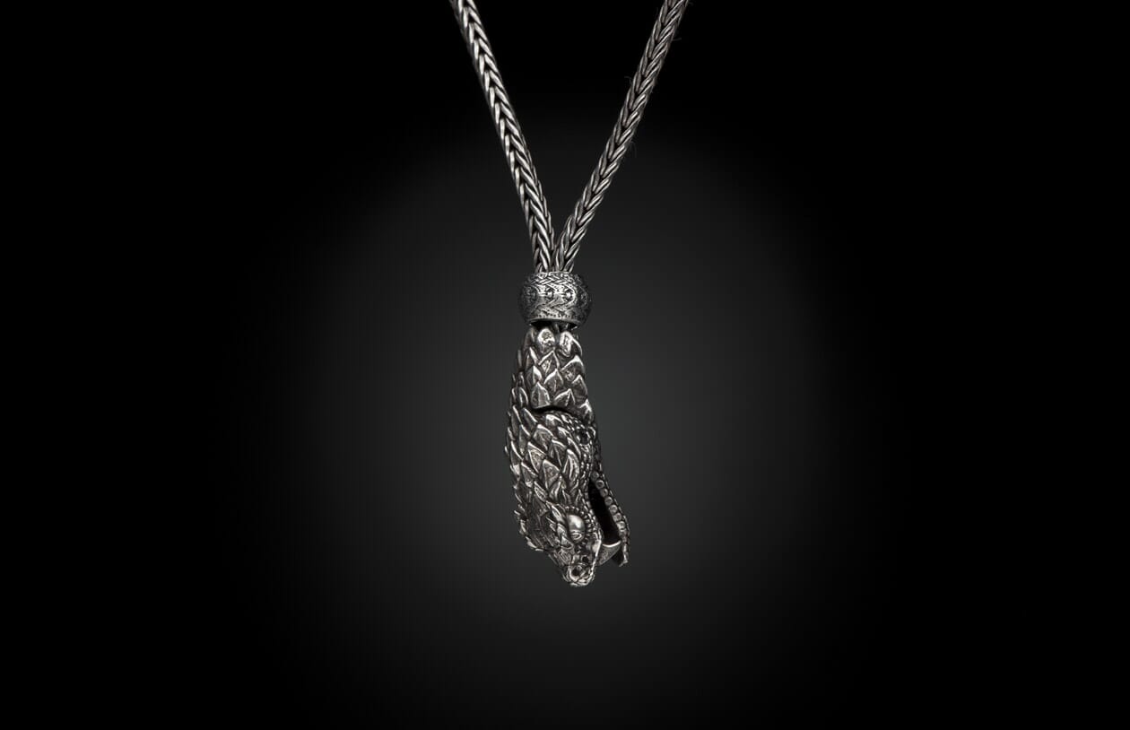 Silver braided necklace with an intricate dragon head pendant featuring scales.