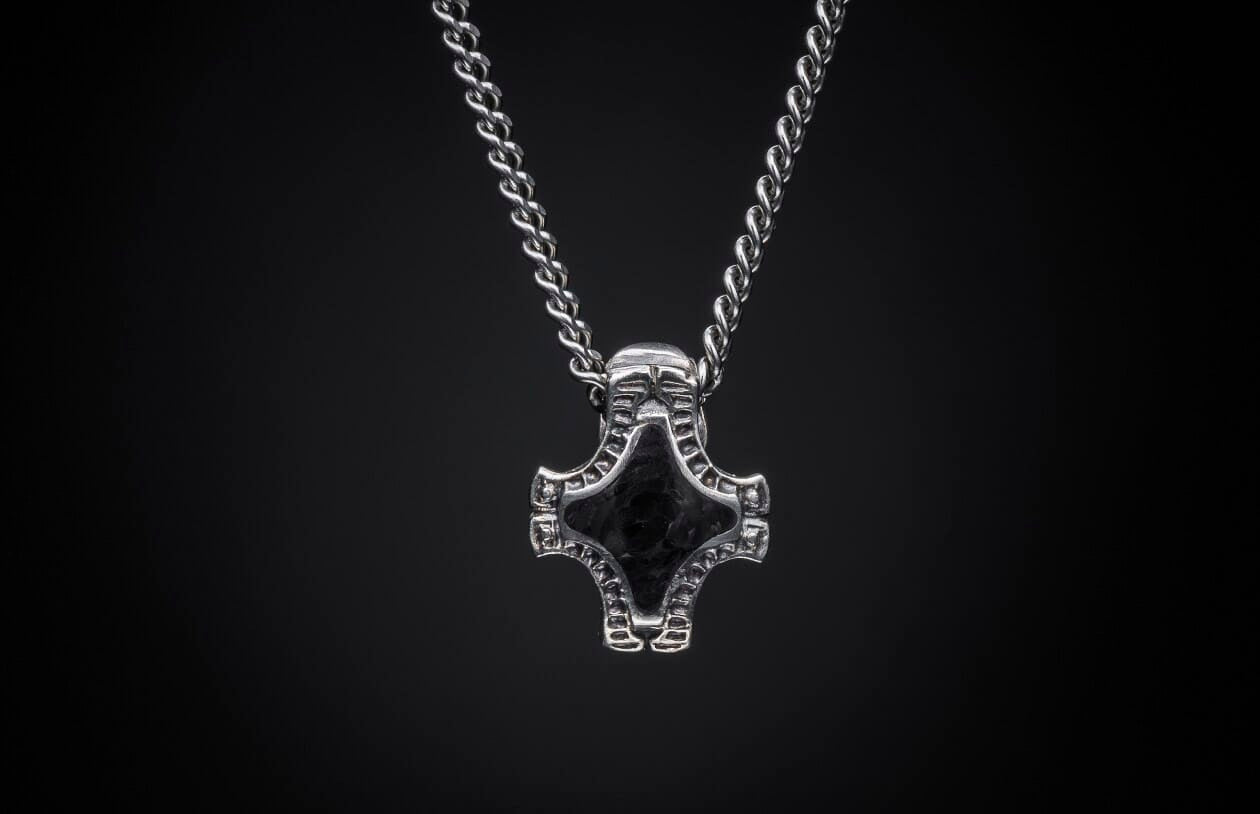 Silver chain necklace with a textured, hammer-shaped pendant featuring a dark center inlay.