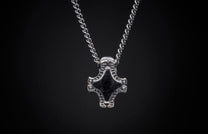 Silver chain necklace with a textured, hammer-shaped pendant featuring a dark center inlay.