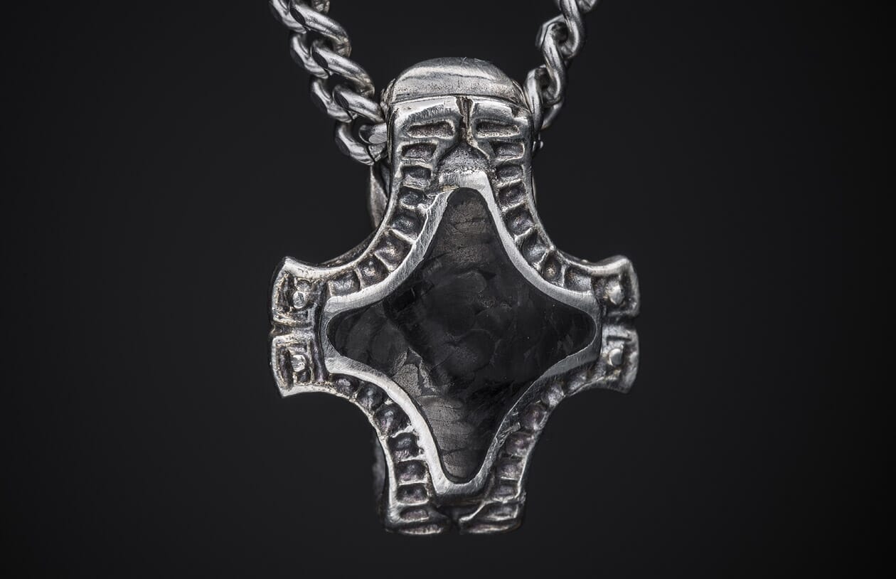 Distressed silver Mjolnir-style pendant featuring a stylized helmet and black textured inlay on a braided chain.