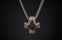 Silver pendant with a mottled reddish-brown stone in an ornate openwork frame, on a twisted chain.