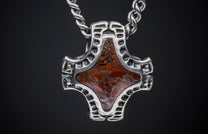 Silver Mjölnir pendant with an oxidized finish and reddish-brown inlay featuring an intricate web-like pattern, on a twisted chain.