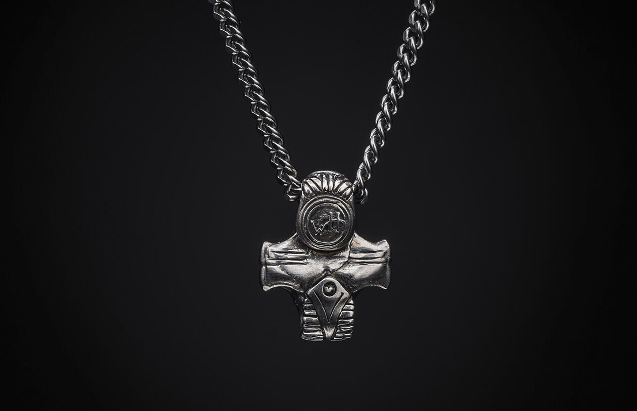Silver-toned metal necklace with a textured curb chain and a stylized hammer-shaped pendant featuring a circular "WH" emblem.