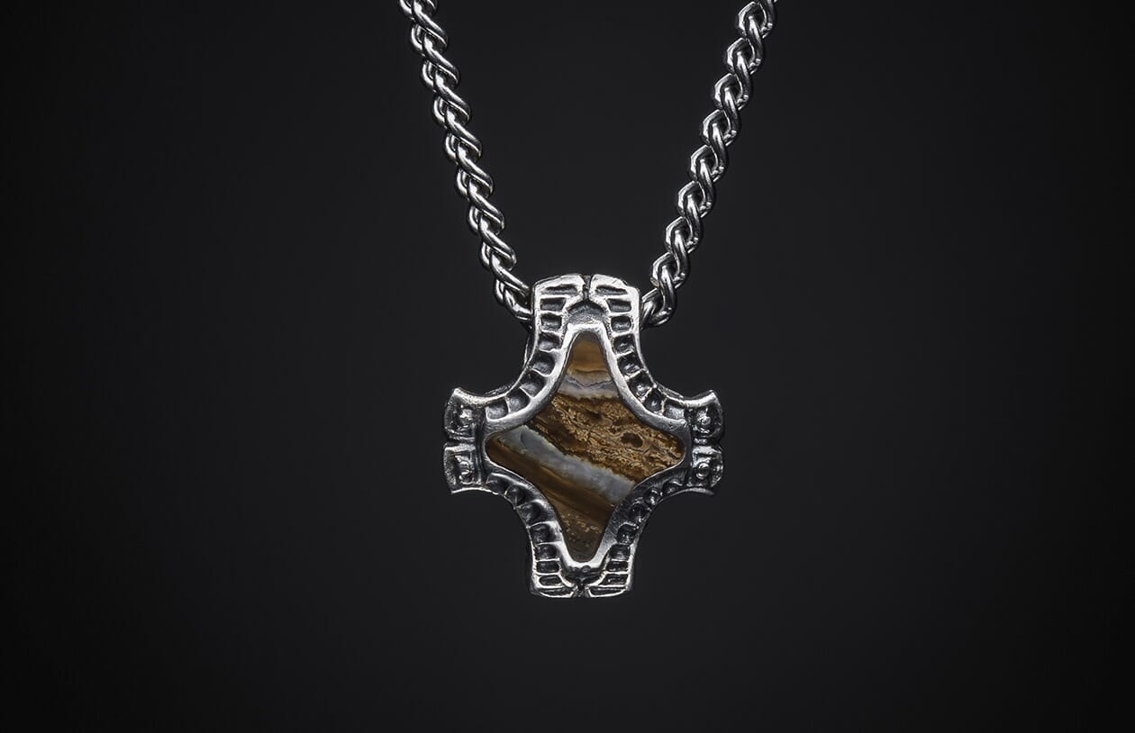 Braided silver-tone chain necklace with a textured metal pendant holding a brown and white layered stone.