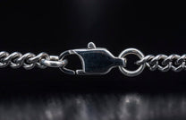 Silver metal chain with a textured lobster clasp closure in a close-up.