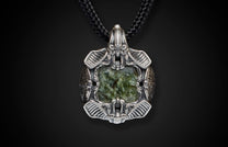 Silver pendant with an intricate alien-insectoid design, centering a rectangular marbled green stone, on a braided black cord.