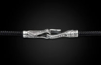 Black braided cord jewelry with an ornate silver hook clasp featuring intricate scrollwork designs.