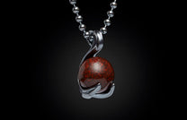 Silver-toned metal necklace pendant holding a spherical dark red stone with black speckled patterns, on a beaded chain.