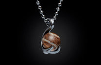 Round brown and white stone pendant in a silver-tone setting on a ball chain, against a black background.