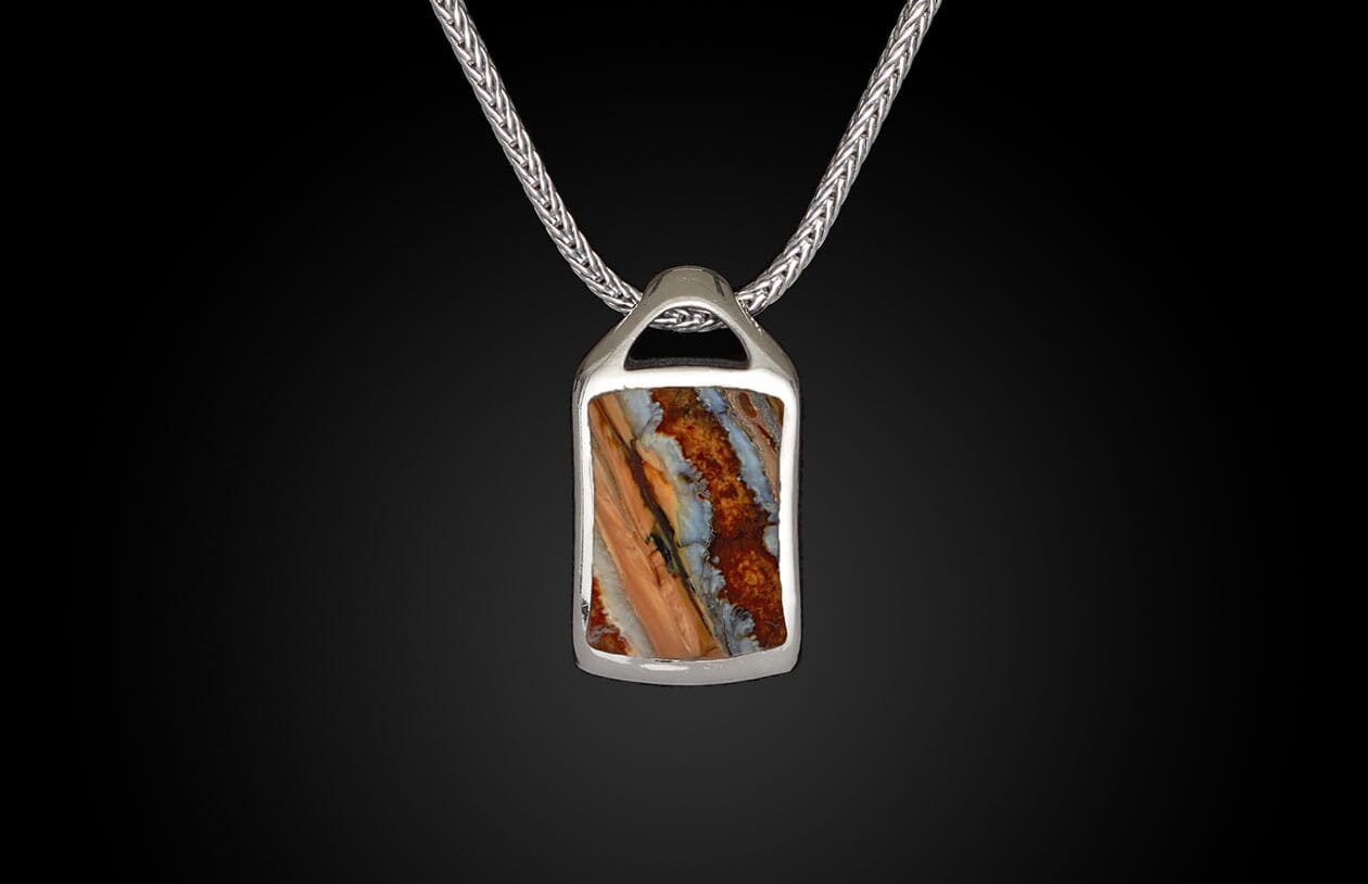 Silver pendant featuring a rectangular, striped stone in orange, blue, and brown on a silver chain.