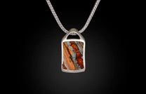 Silver pendant featuring a rectangular, striped stone in orange, blue, and brown on a silver chain.