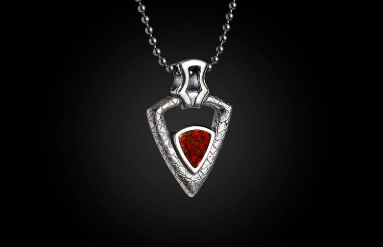 Triangular silver pendant with a textured finish and a red fossilized inlay, hanging from a metal bead chain.