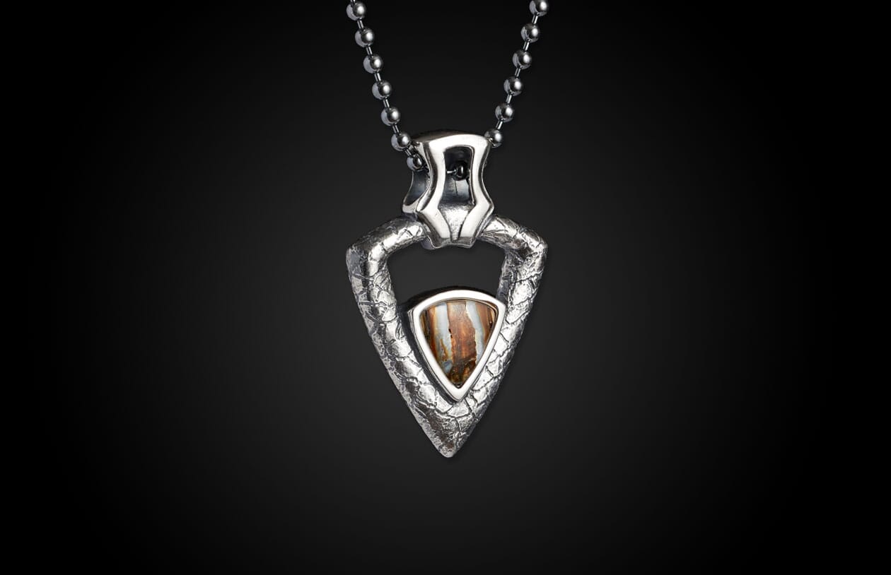 Silver textured triangular pendant necklace with a central brown striped stone, suspended from a ball chain.