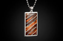 Rectangular silver-toned pendant featuring a striped stone in warm orange, brown, and white, suspended from a ball chain.