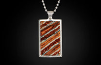 Silver rectangular pendant with diagonally striped orange, reddish-brown, and white stone inlay, on a ball chain.