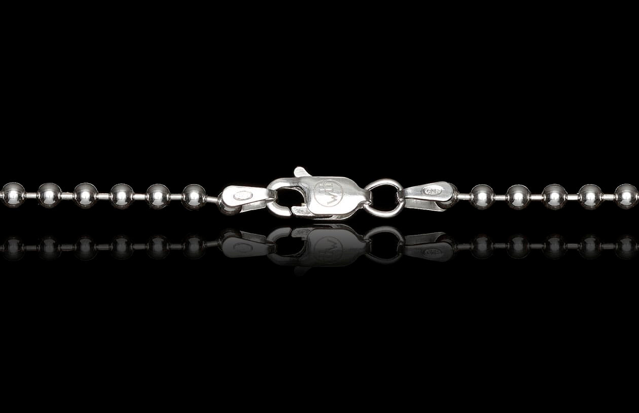 Silver ball chain necklace with an engraved lobster clasp, displayed with a mirrored reflection.