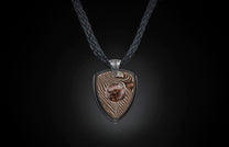 Pendant necklace with a shield-shaped pendant made of wavy patterned metal and a central reddish-brown stone, on a black braided cord.