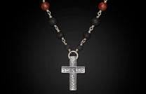 Silver-toned textured cross necklace with black lava beads and reddish-brown patterned beads.