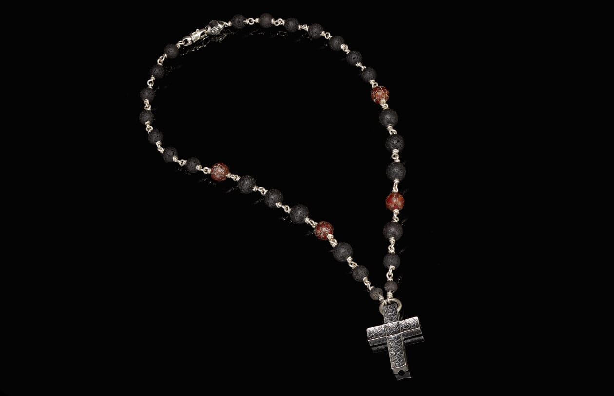 Black lava stone beaded rosary with reddish-brown accent beads and a textured silver-tone cross pendant.