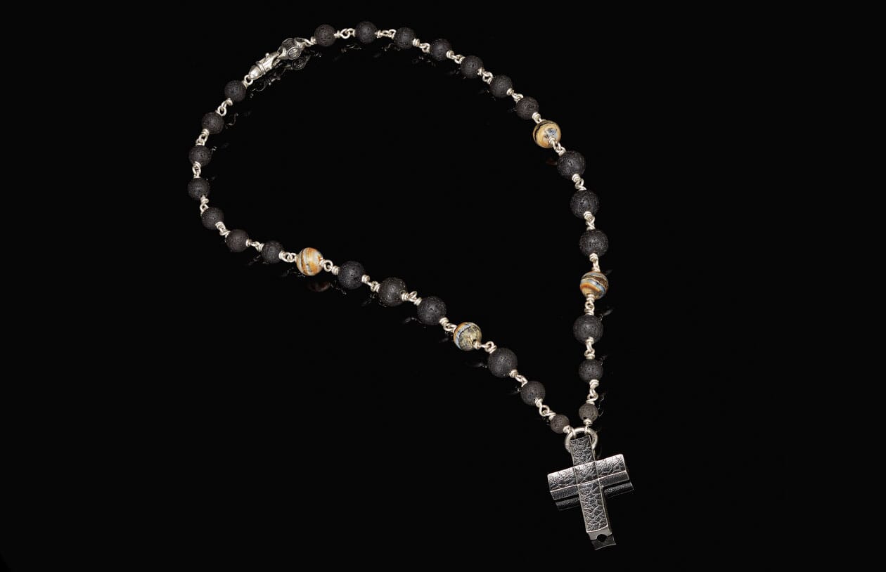 Black lava rosary-style necklace with patterned accent beads and a textured silver cross pendant.