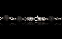 Sodalite Crux beaded chain with black porous lava stone beads, silver links, a central engraved charm, and a lobster clasp.