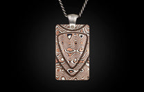 Rectangular mokume-gane pendant by Mokume Forge with a silver chain, featuring a swirling copper and silver wood-grain pattern and textured bail.