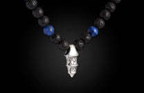 Necklace with black lava and blue sodalite beads, featuring a multi-tiered silver-toned pendant with textured scales.