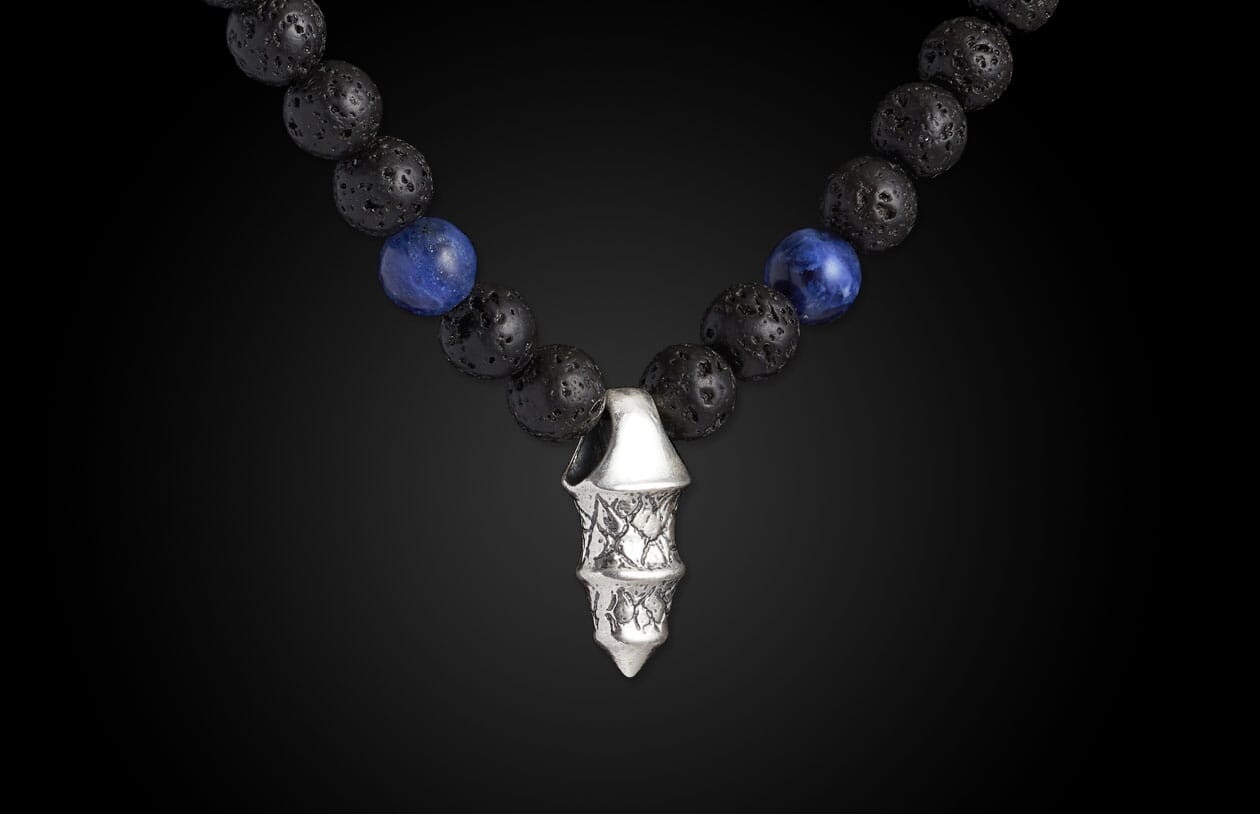 Necklace with black lava and blue sodalite beads, featuring a multi-tiered silver-toned pendant with textured scales.