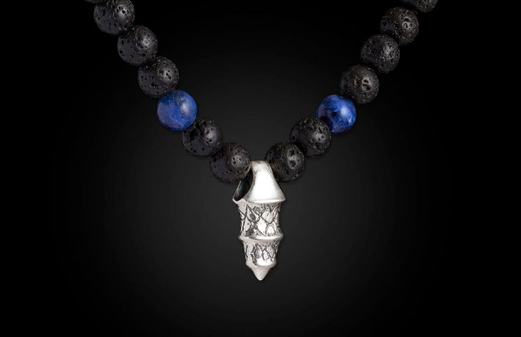 Necklace with black lava and blue sodalite beads, featuring a multi-tiered silver-toned pendant with textured scales.