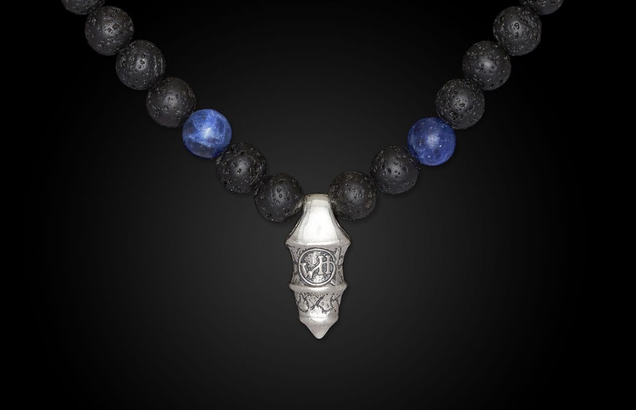 Sodalite necklace with blue sodalite and black lava beads, featuring a textured silver-toned pendant with carved details.