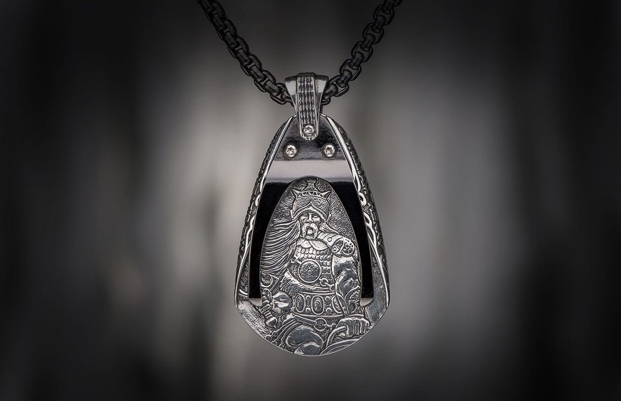 Silver warrior pendant with ornate details, depicting a crowned figure, hanging from a dark chain.