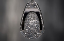 Silver-toned metal pendant featuring an intricately engraved warrior in a helmet, holding a sword.