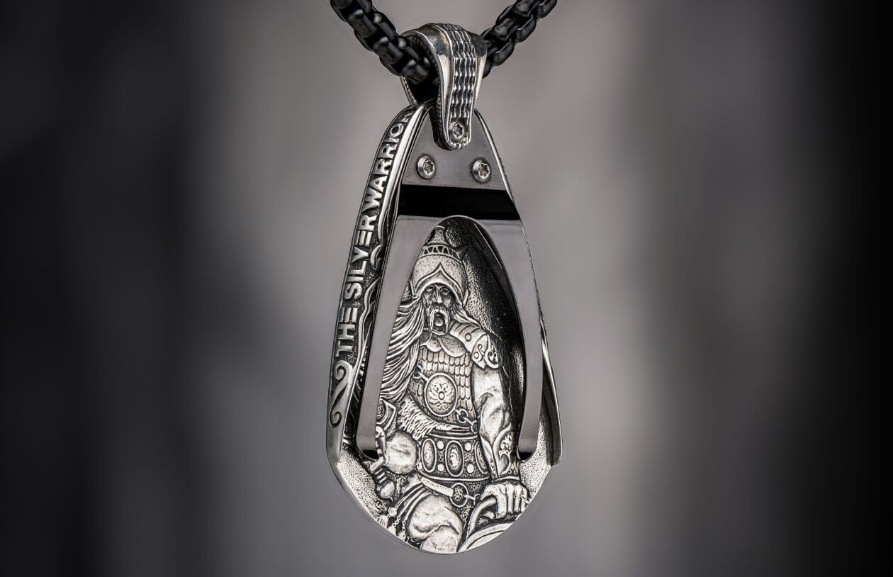 Silver pendant featuring an intricately detailed warrior figure and "THE SILVER WARRIOR" text on a black chain.