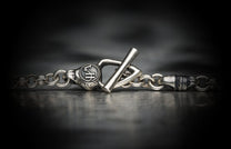 Silver-toned metal bracelet with a textured toggle clasp, featuring circular detail with "WH" initials and thick chain links.