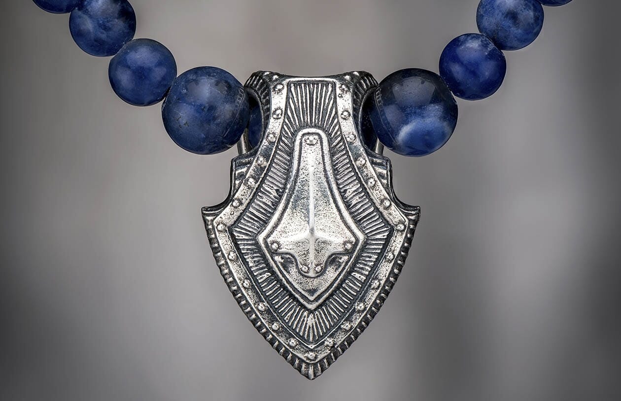 Sodalite shield pendant necklace in silver and blue sodalite, with intricate etched details.