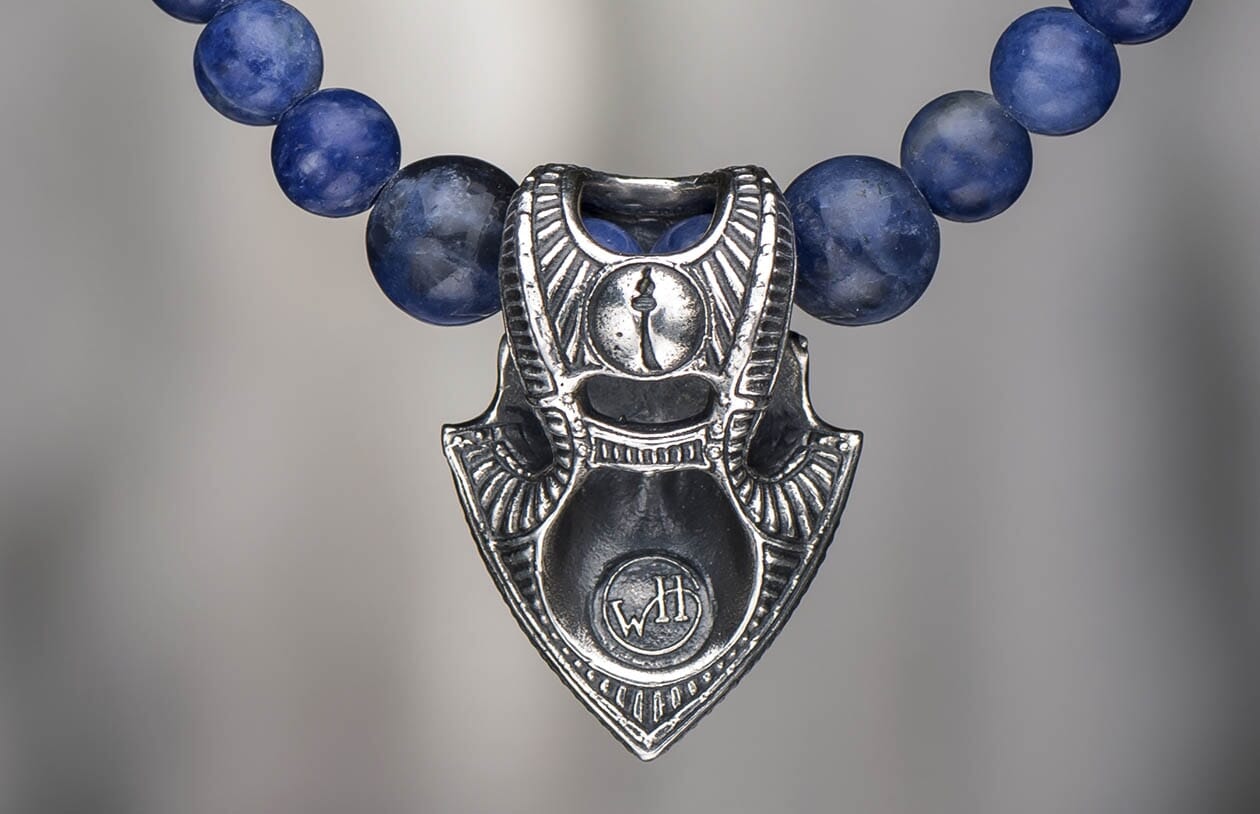 Sodalite Shield jewelry with a detailed silver-toned metal pendant featuring a keyhole design and 'WH' initials, strung with dark blue sodalite beads.