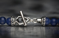 Sodalite bead bracelet with a silver metal toggle clasp, featuring ornate silver end caps and matte blue sodalite beads.