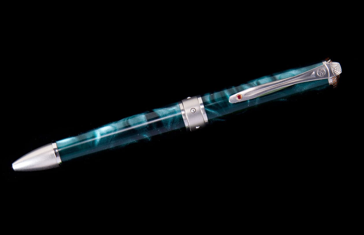 Marbled teal pen with silver metal tip, central band, and a clip featuring a small red gem.