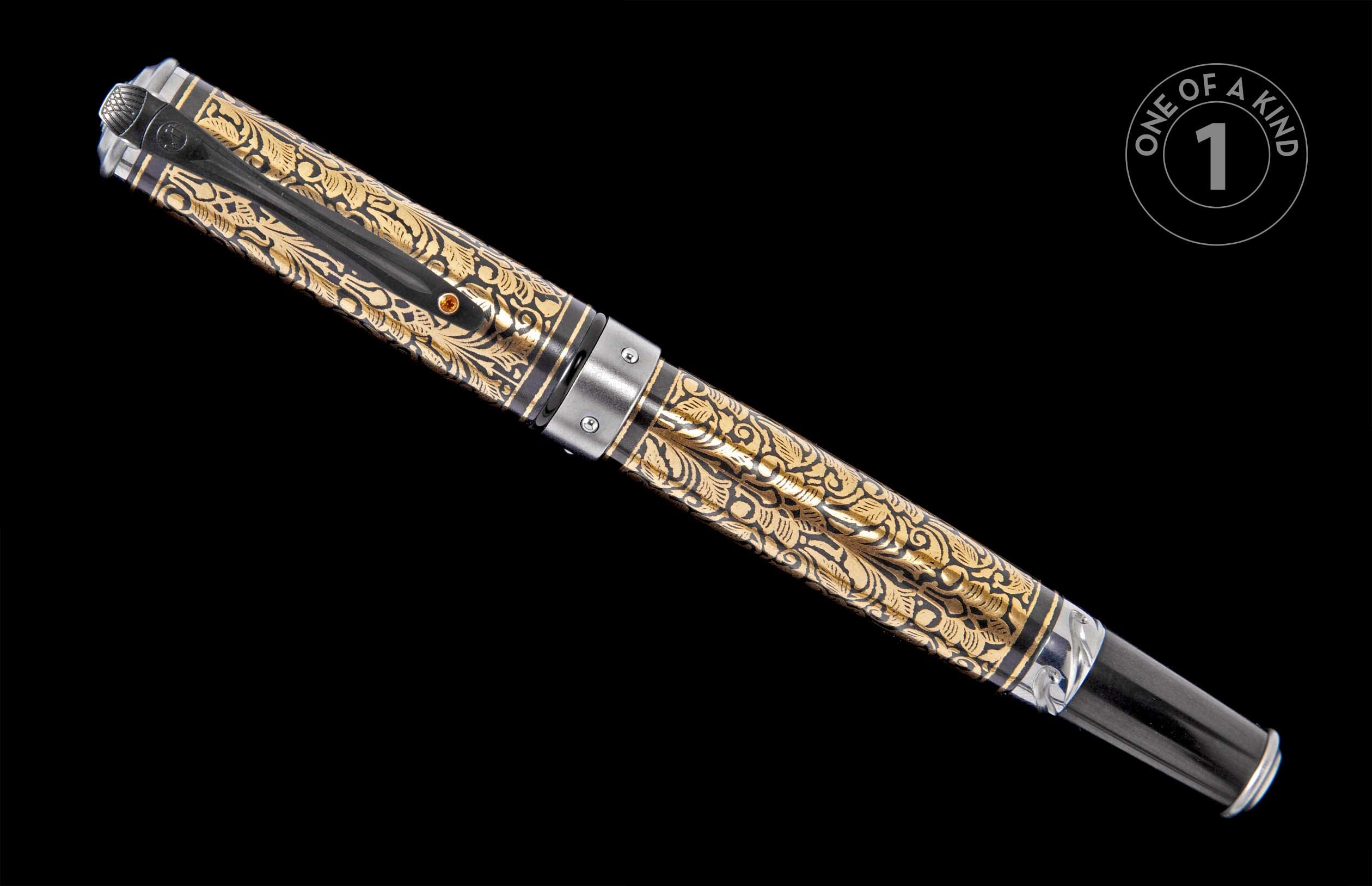 Ornate gold and black etched pen with intricate floral patterns, featuring a dark metal clip and tip, angled.